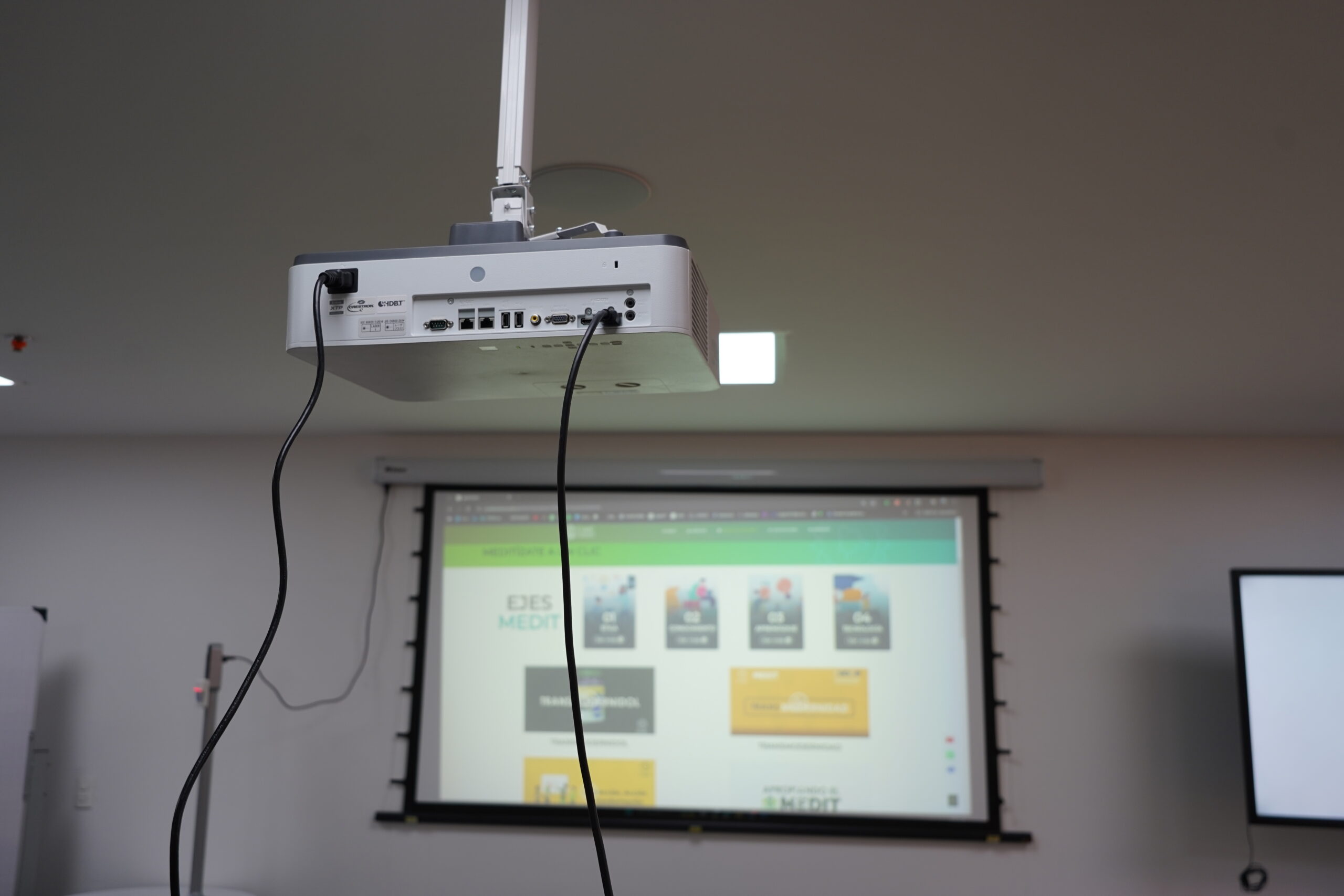 Videoproyector de techo apuntando a la pantalla del aula