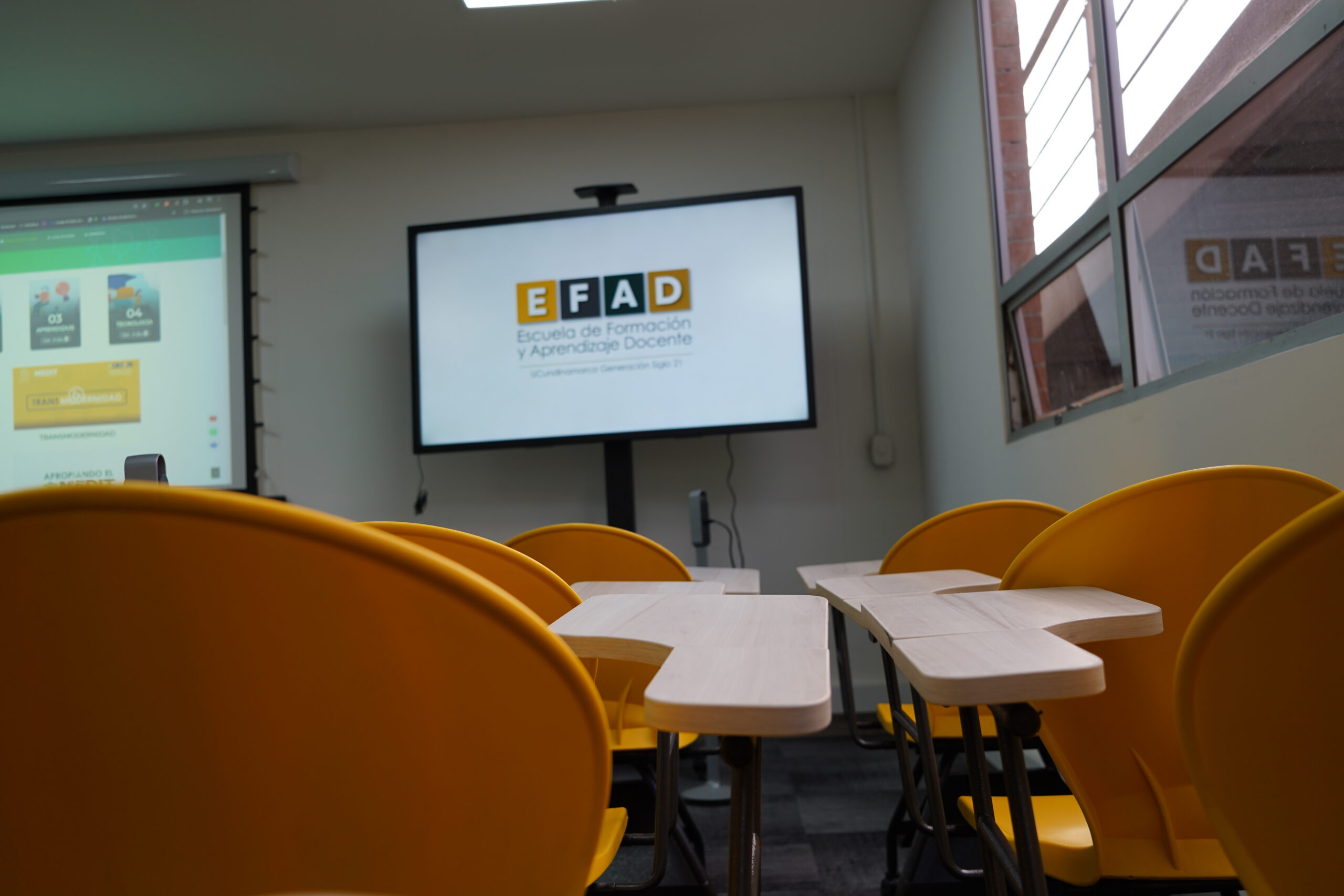 Aula con sillas amarillas y pantalla con el logo de la EFAD
