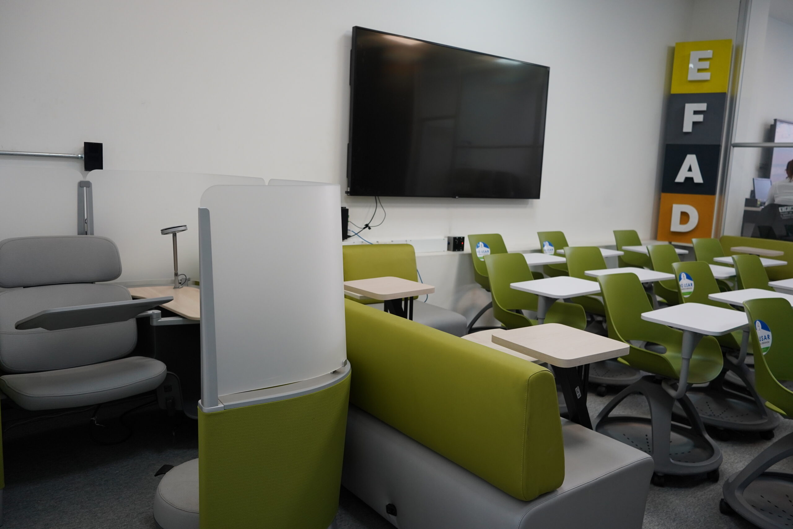 Aula con pupitres verdes móviles, televisor y las letras EFAD en la pared