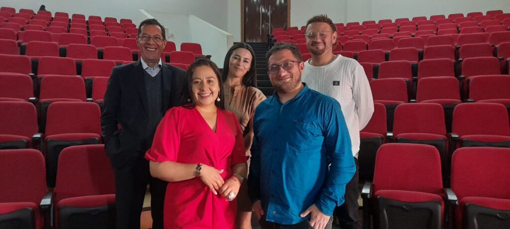 Cinco integrantes del equipo organizador posan de pie entre las butacas rojas del auditorio en los Premios El Pensador IPA 2025.